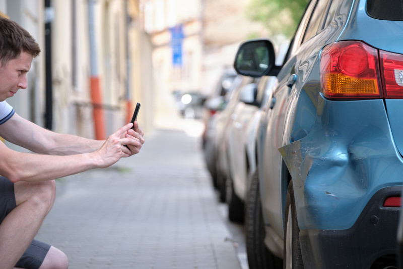 Person taking photos of car accident damage for an insurance claim after a traffic collision