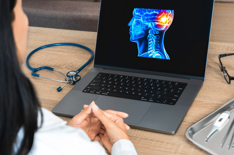 Female doctor reviewing digital brain scan on laptop showing head trauma
