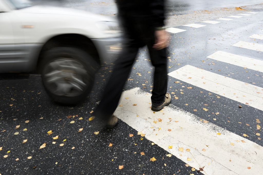 Jaywalking Man with crutches crossing a street